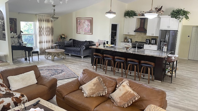 kitchen featuring decorative light fixtures, white cabinetry, wall chimney exhaust hood, tasteful backsplash, and stainless steel refrigerator with ice dispenser