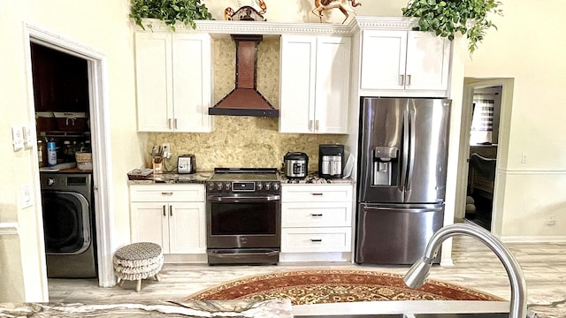 kitchen featuring stainless steel appliances, washer / clothes dryer, white cabinets, and wall chimney exhaust hood