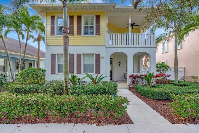 view of front of property featuring stucco siding, a balcony, covered porch, and ceiling fan