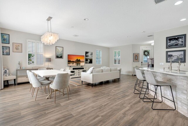 dining space featuring sink, an inviting chandelier, a textured ceiling, and light wood-type flooring