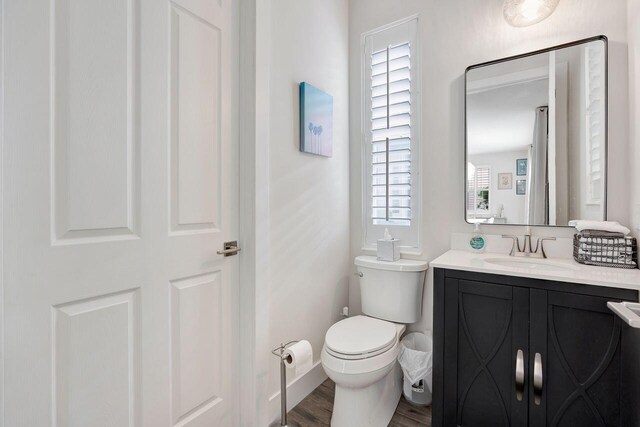 bathroom with hardwood / wood-style flooring, vanity, toilet, and a wealth of natural light