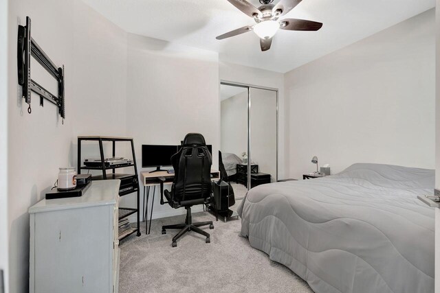 bedroom featuring light colored carpet, ceiling fan, and a closet