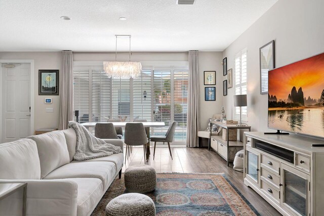 living room featuring an inviting chandelier, light hardwood / wood-style floors, and a textured ceiling