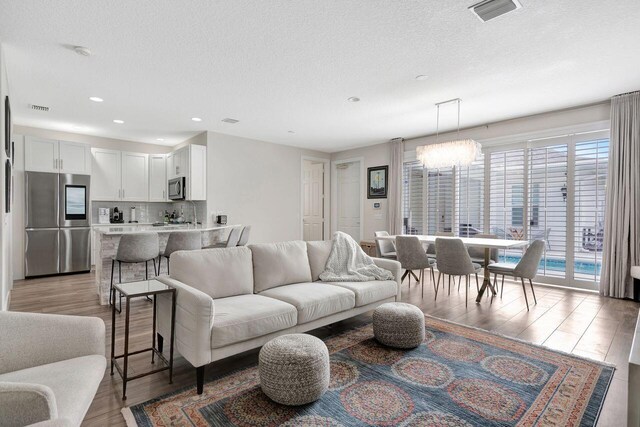 living room featuring a notable chandelier, light hardwood / wood-style floors, and a textured ceiling