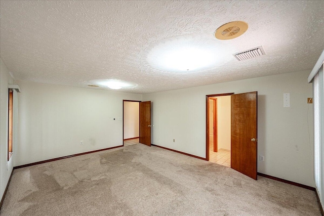 empty room with a textured ceiling and light carpet