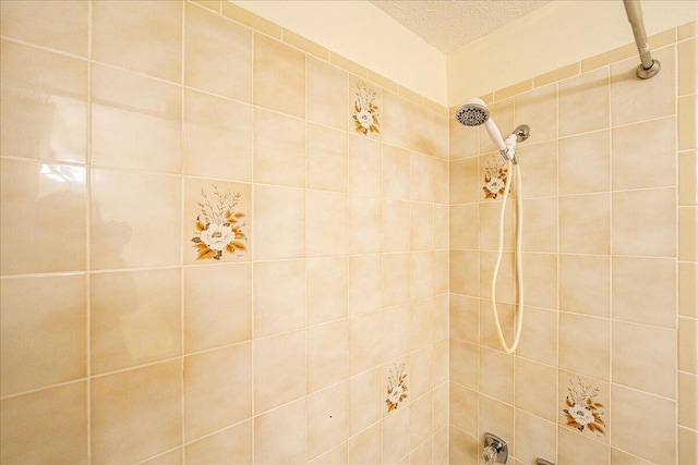 bathroom featuring a textured ceiling and tiled shower / bath