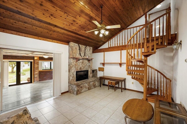 living room with light tile patterned floors, wood ceiling, lofted ceiling, ceiling fan, and a stone fireplace