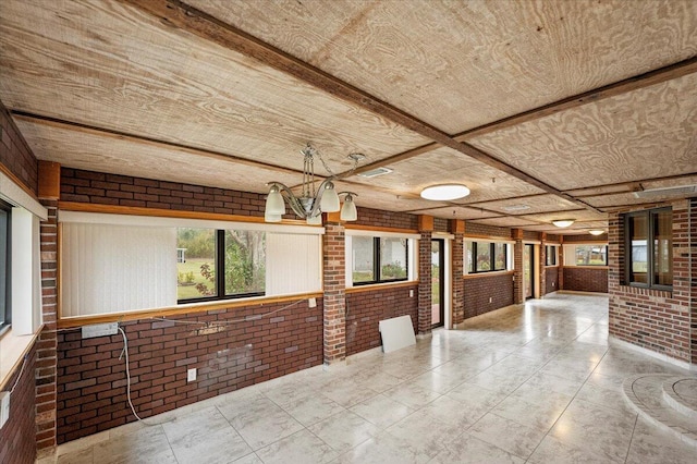 interior space with brick wall, a notable chandelier, and coffered ceiling