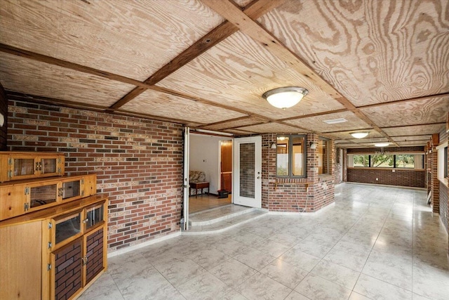 unfurnished living room with brick wall, french doors, and coffered ceiling