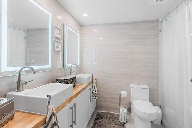 bathroom with toilet, vanity, tile walls, and curtained shower