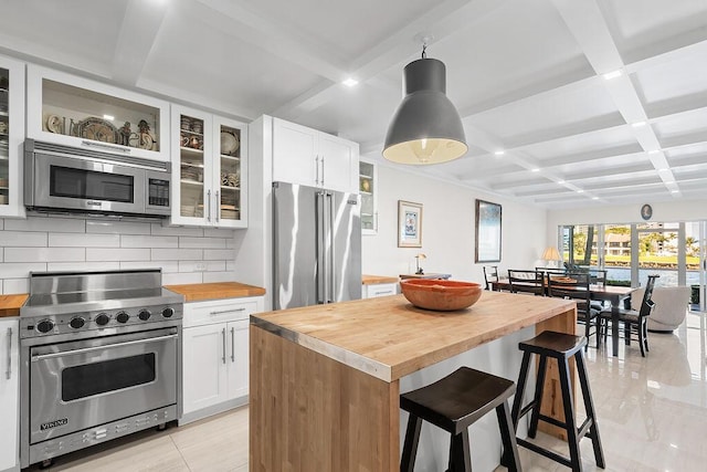 kitchen featuring coffered ceiling, butcher block countertops, backsplash, and premium appliances