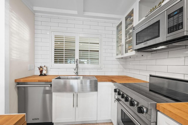 kitchen with sink, stainless steel appliances, wood counters, and white cabinetry