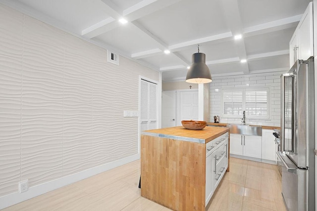 kitchen featuring wooden counters, stainless steel fridge, coffered ceiling, and white cabinetry