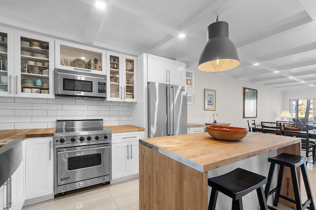 kitchen with butcher block counters, coffered ceiling, backsplash, and premium appliances