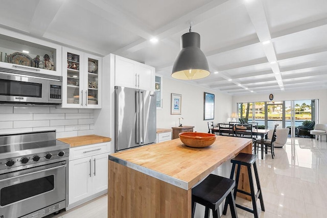 kitchen featuring high quality appliances, white cabinets, backsplash, and coffered ceiling