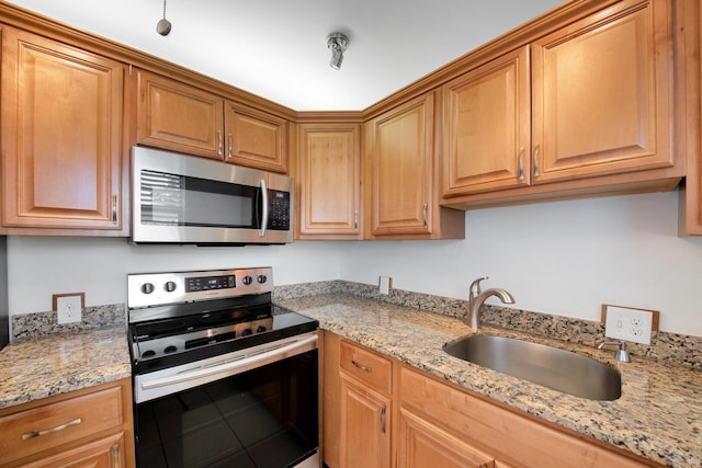 kitchen with appliances with stainless steel finishes, light stone counters, and sink