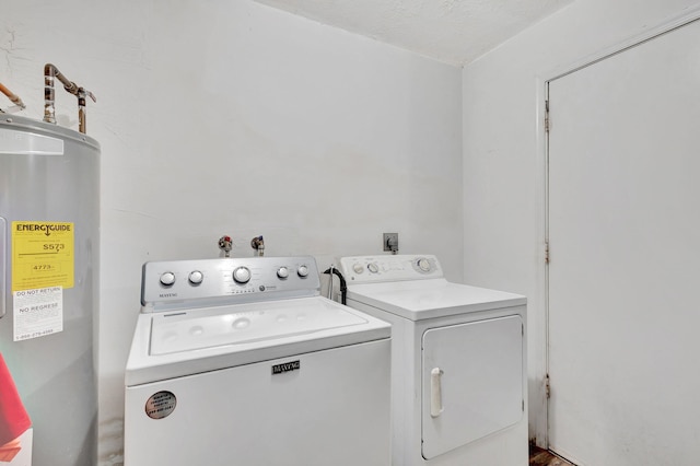 washroom with water heater, a textured ceiling, and washer and clothes dryer