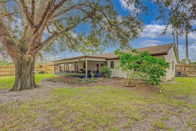 rear view of house featuring a sunroom, a yard, and central air condition unit