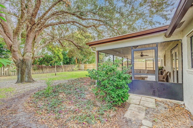 view of yard featuring ceiling fan and a sunroom