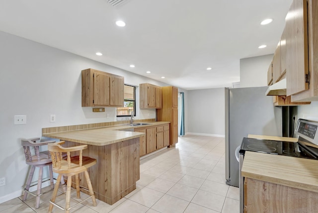 kitchen with a kitchen breakfast bar, sink, kitchen peninsula, stainless steel electric range oven, and light tile patterned floors