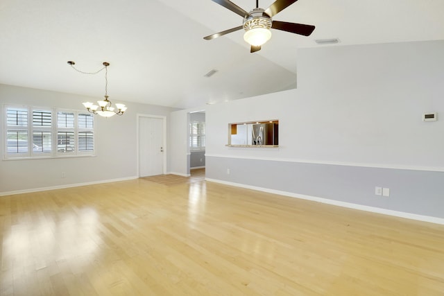 unfurnished living room featuring ceiling fan with notable chandelier, light hardwood / wood-style floors, a wealth of natural light, and vaulted ceiling