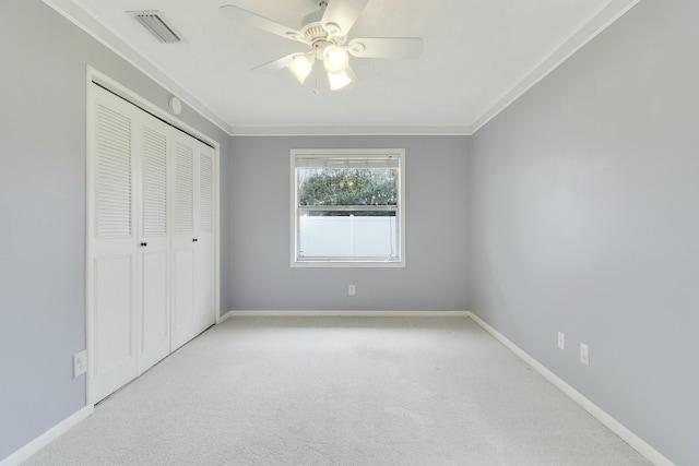 unfurnished bedroom with light carpet, a closet, ceiling fan, and ornamental molding