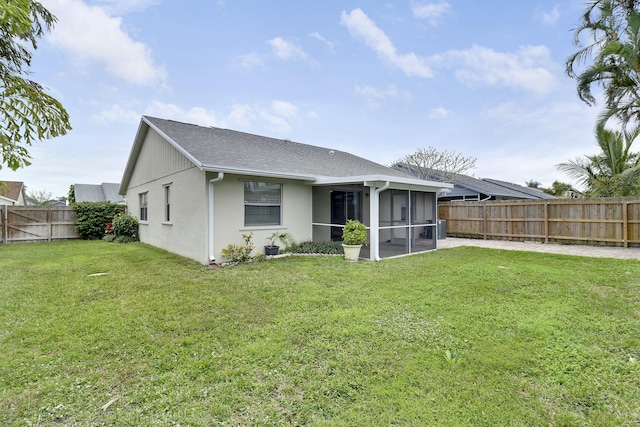 rear view of property featuring a sunroom and a lawn