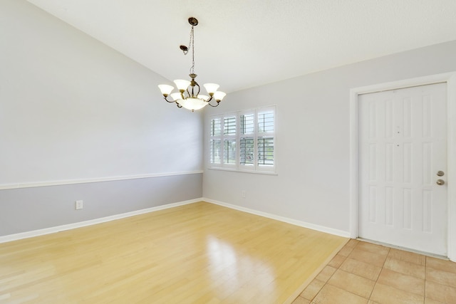 spare room featuring light wood-type flooring and an inviting chandelier