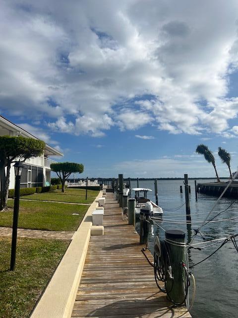 view of dock with a yard and a water view