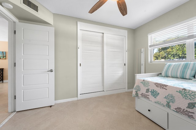 tiled bedroom featuring ceiling fan and a closet