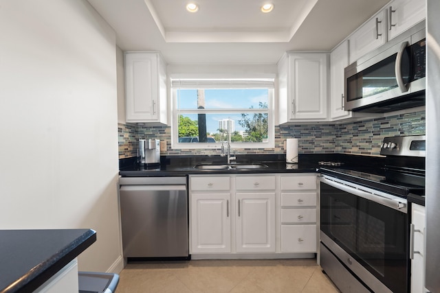 kitchen with white cabinetry, sink, a tray ceiling, and appliances with stainless steel finishes