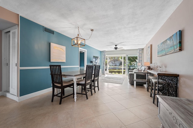 tiled dining room featuring ceiling fan with notable chandelier and a textured ceiling