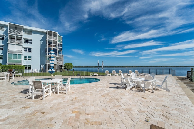 view of swimming pool featuring a water view and a patio