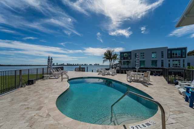 view of swimming pool with a patio and a water view