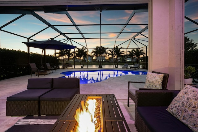 pool at dusk with glass enclosure, an outdoor living space with a fire pit, and a patio