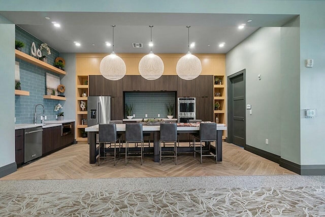 kitchen with a kitchen bar, light parquet floors, appliances with stainless steel finishes, and a center island