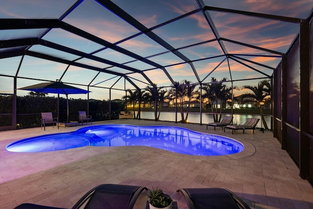 pool at dusk featuring a lanai, a water view, and a patio area