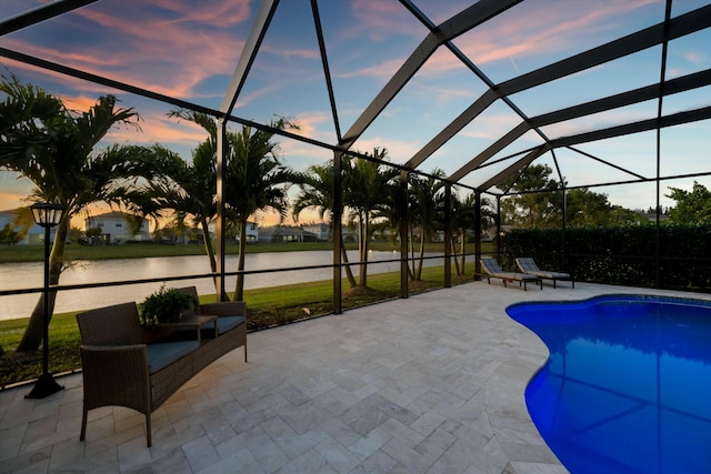 pool at dusk with a patio area, a lanai, and a water view