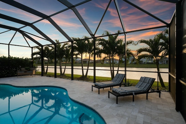 pool at dusk with a water view, a patio, and a lanai