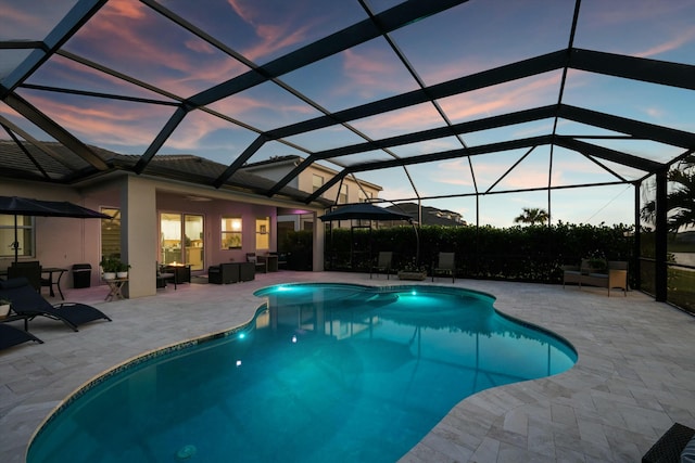 pool at dusk with a lanai and a patio