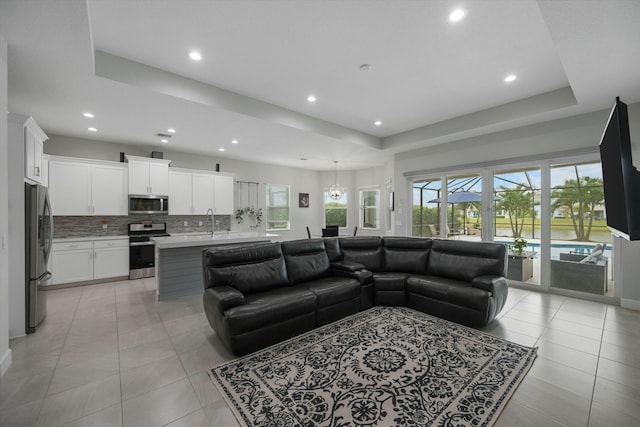 living room featuring light tile patterned floors, a tray ceiling, and sink