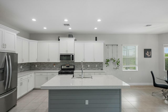 kitchen with white cabinets, appliances with stainless steel finishes, sink, and an island with sink