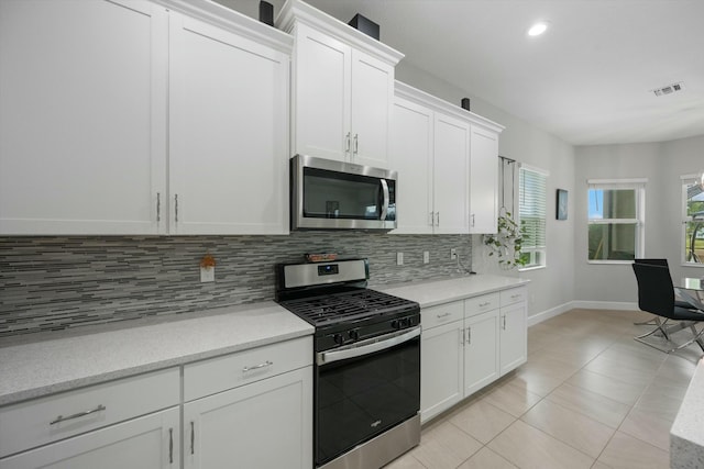 kitchen with light tile patterned floors, white cabinetry, appliances with stainless steel finishes, and tasteful backsplash