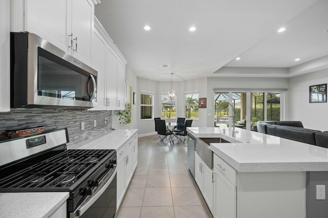 kitchen with white cabinetry, stainless steel appliances, tasteful backsplash, sink, and a kitchen island with sink