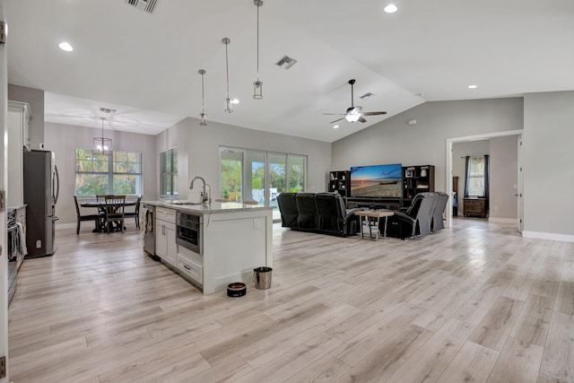 kitchen with decorative light fixtures, ceiling fan, a center island with sink, white cabinetry, and appliances with stainless steel finishes