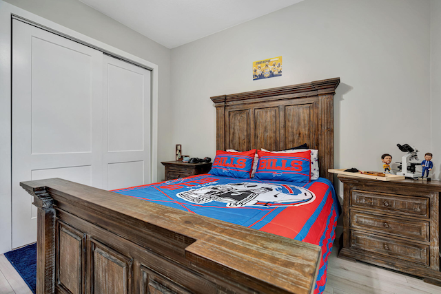 bedroom with light wood finished floors and a closet