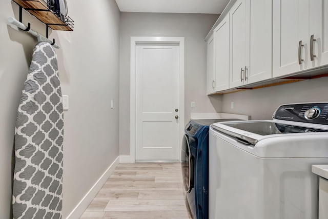 laundry room featuring light wood-type flooring, cabinet space, baseboards, and washing machine and clothes dryer