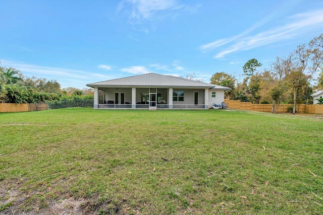 rear view of house featuring a sunroom, fence, metal roof, and a yard