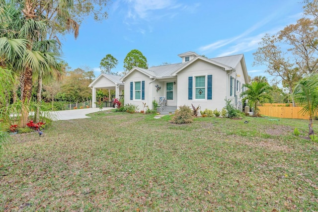 view of front of house with metal roof, an attached carport, fence, concrete driveway, and a front lawn