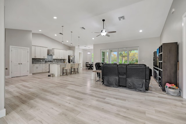 living room with ceiling fan, light hardwood / wood-style floors, and high vaulted ceiling